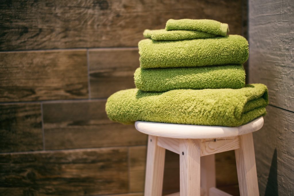 THREE GREEN TOWELS SITTING ON A BAR STOOL