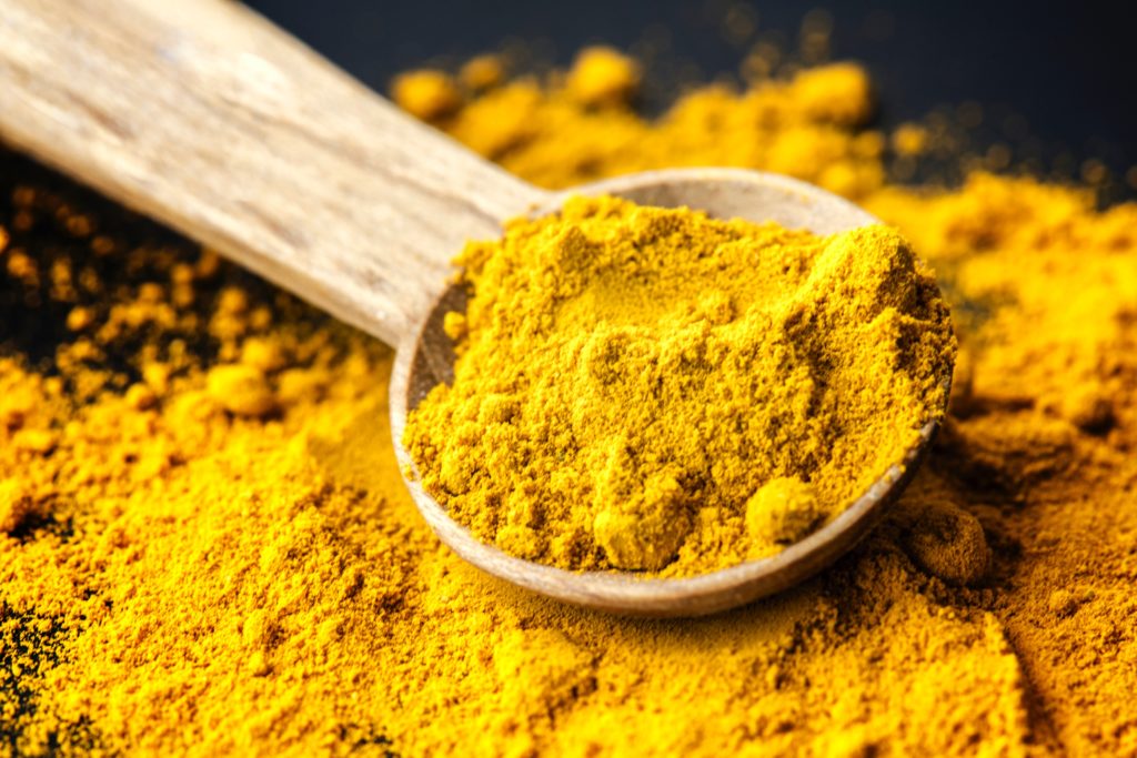 POWDERED YELLOW TURMERIC AND SPOON
